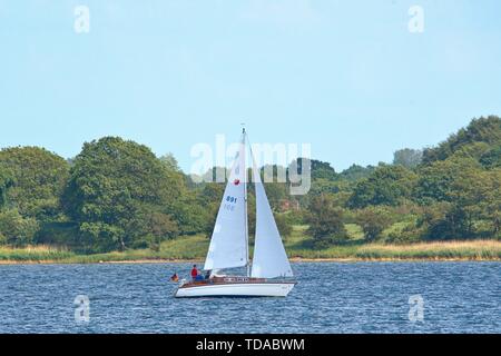 Schleswig, Deutschland. 09 Juni, 2019. 09.06.2019, die Schlei in Schleswig. Die ostseefjord, ein Ostsee Einlass mit brackigem Wasser gefüllt, ist ein beliebtes Segelrevier. Ein Segelboot auf dem Wasser, im Hintergrund sind Stexwig und Fahrdorf. | Verwendung der weltweiten Kredit: dpa/Alamy leben Nachrichten Stockfoto