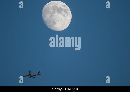 London, Großbritannien. 14. Juni 2019. Ein kommerzielles Flugzeug fliegt unter einem großen gibbous Mond am Abend Credit: Amer ghazzal/Alamy leben Nachrichten Stockfoto