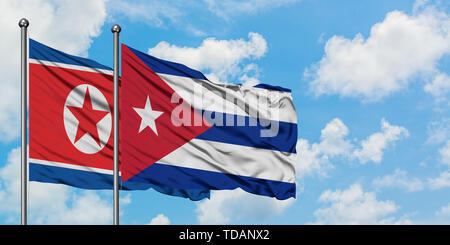 Nordkorea und Kuba Flagge im Wind gegen Weiße bewölkt blauer Himmel zusammen. Diplomatie Konzept, internationale Beziehungen. Stockfoto