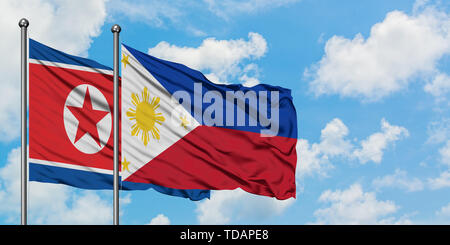 Nordkorea und Flagge Philippinen winken im Wind gegen Weiße bewölkt blauer Himmel zusammen. Diplomatie Konzept, internationale Beziehungen. Stockfoto