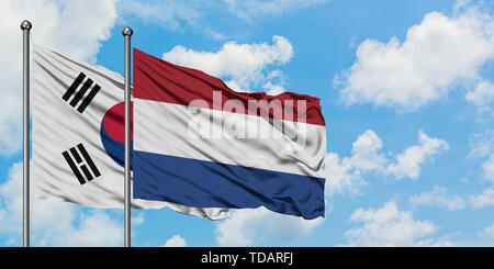 Südkorea und Niederlande Flagge im Wind gegen Weiße bewölkt blauer Himmel zusammen. Diplomatie Konzept, internationale Beziehungen. Stockfoto