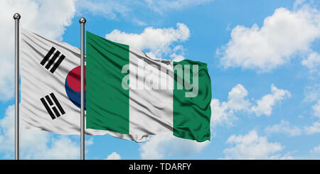 Südkorea und Nigeria Flagge im Wind gegen Weiße bewölkt blauer Himmel zusammen. Diplomatie Konzept, internationale Beziehungen. Stockfoto