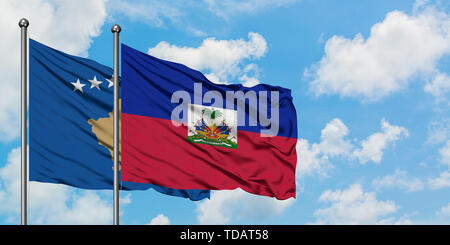 Kosovo und Haiti Flagge im Wind gegen Weiße bewölkt blauer Himmel zusammen. Diplomatie Konzept, internationale Beziehungen. Stockfoto