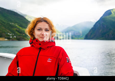 Rothaarige sommersprossige junge Frau in der roten Jacke. Stockfoto