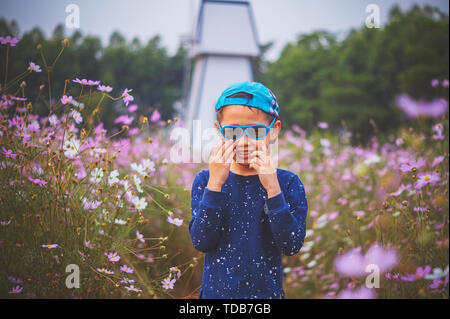 Der junge stehend in den Blumen. Stockfoto