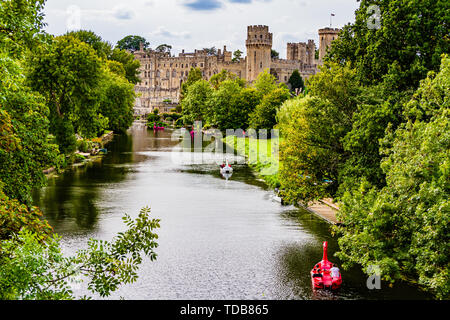 Warwick Castle mit Touristen in Mieten Boote auf dem Fluss Avon. Warwick, Warwickshire, Großbritannien. Sommer 2018. Stockfoto