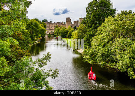 Warwick Castle mit Touristen in Mieten Boote auf dem Fluss Avon. Warwick, Warwickshire, Großbritannien. Sommer 2018. Stockfoto