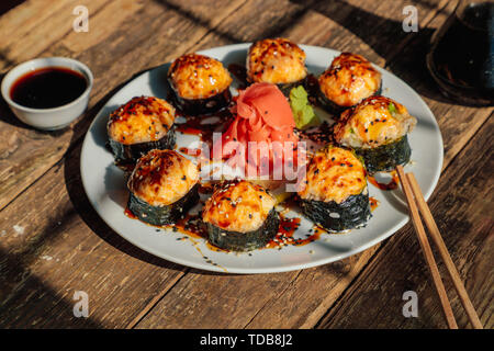 Gebackene japanischen Rollen in einem weißen Teller auf einem alten Holztisch Stockfoto