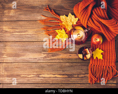Trinken Herbst apple rote Beeren in eine Teekanne aus Glas und eine orangefarbene Schal auf einer hölzernen Hintergrund. Hot fruit Berry Tee. Stockfoto