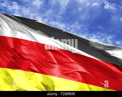 Wehende Flagge Südossetiens close up gegen den blauen Himmel Stockfoto