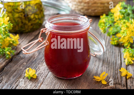 Ein Glas roten Öl aus Johanniskraut Blüten erfolgen Stockfoto