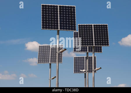 Sonnenkollektoren auf den Säulen der LED-Straßenbeleuchtung gegen den blauen Himmel mit Wolken Stockfoto