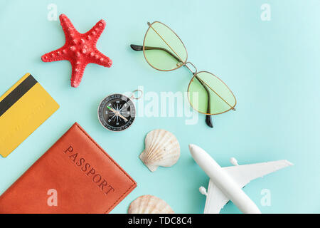 Ferienhäuser reisen Abenteuer Reise Konzept. Minimale einfach flach mit dem Flugzeug pass Sonnenbrille Kompass Gold Kreditkarte Shell auf Blau Pastell farbenfrohen trendigen Hintergrund. Touristische Essentials Stockfoto