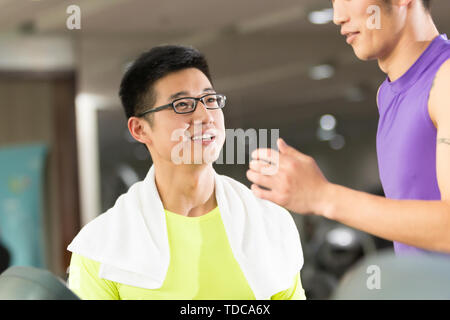 Junge asiatische Männer und trainieren Sie im modernen Fitnessraum Stockfoto