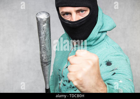 Eine maskierte Hooligan hält einen Baseballschläger in der Hand Stockfoto