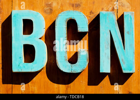 Hellblau Holz- dreidimensionalen Buchstaben bilden den Text BCN, eine Abkürzung für Barcelona, Spanien, auf einer hölzernen Hintergrund Stockfoto