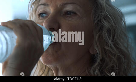 Ältere Frau Getränke Wasser aus Trinkwasser in der Turnhalle, in der Nähe Stockfoto