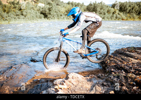 Professionelle gut ausgestattete Radfahrer reiten auf dem felsigen Riverside in den Bergen. Konzept der Freeride- und off road Radfahren Stockfoto