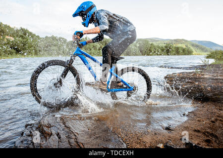 Professionelle gut ausgestattete Radfahrer reiten auf dem felsigen Riverside in den Bergen. Konzept der Freeride- und off road Radfahren Stockfoto