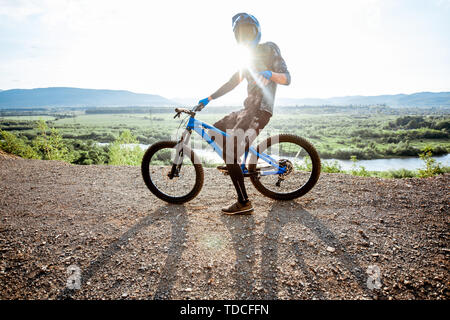 Professionelle gut ausgestattete Radfahrer reiten Fahrrad auf der Rocky Mountains mit Blick auf die schöne Landschaft bei Sonnenuntergang Stockfoto