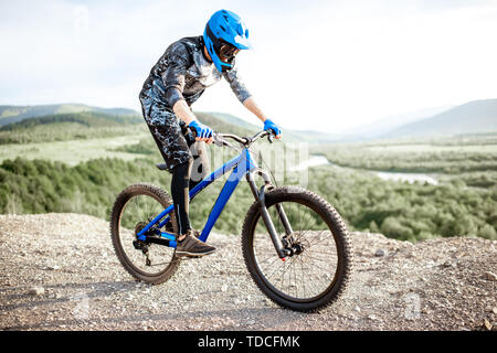 Professionelle gut ausgestattete Radfahrer reiten Fahrrad auf der Rocky Mountains mit Blick auf die schöne Landschaft bei Sonnenuntergang Stockfoto