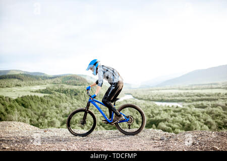 Professionelle gut ausgestattete Radfahrer reiten Fahrrad auf der Rocky Mountains mit Blick auf die schöne Landschaft bei Sonnenuntergang Stockfoto