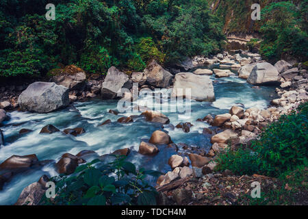 Blick auf den Fluss Urubamba unter dem Machu Picchu Mountain. Starke Wasserströmung fließen, große polierte Steine im Tal. Stockfoto