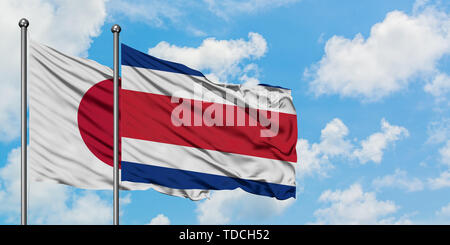 Japan und Costa Rica Flagge im Wind gegen Weiße bewölkt blauer Himmel zusammen. Diplomatie Konzept, internationale Beziehungen. Stockfoto