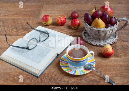 Herbst noch Leben mit verschiedenen Gaben der Natur. Tasse Tee und offenes Buch liegen auf einem Schreibtisch aus Holz. Konzeption der Liebe. Stockfoto