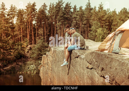 Schönes angenehmes Paar sitzt auf einem Kliff Stockfoto