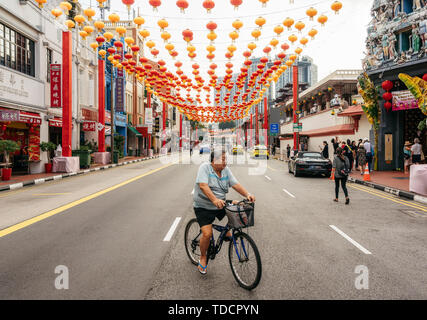 Chinatown, Singapur - Februar 8, 2019: Alter Mann fährt mit dem Fahrrad auf South Bridge Road in der Nähe von Sri Mariamman Tempel in der Chinatown mit bunten Laternen Stockfoto