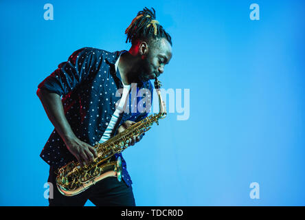 Junge afrikanische-amerikanischen Jazz musiker Saxophon auf Blau studio Hintergrund in trendigen Neon Licht. Konzept der Musik, Hobby. Freudige attraktiver Kerl improvisieren. Retro bunte Porträt des Künstlers. Stockfoto