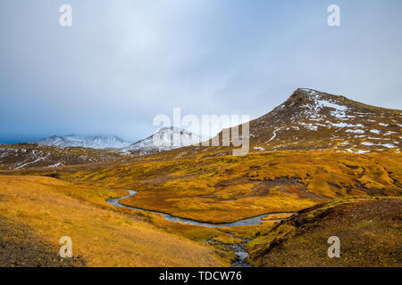 Schwarz Snowy Mountains und Grasland Herbst Landschaft Islands in Wolken versteckt Stockfoto