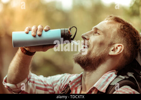 Schönes erfreut, bärtigen Mann hält eine Thermosflasche Stockfoto