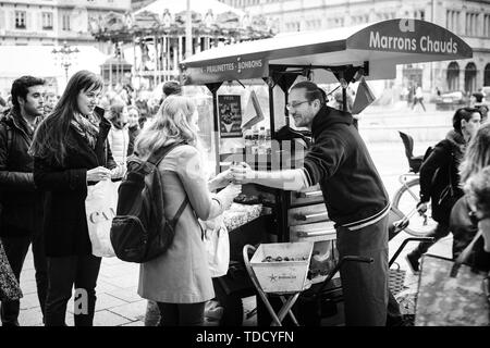 Straßburg, Frankreich - 28 Oktober 2017: Ambulante männliche Verkäufer von heissen Kastanien marron chauds auf den Straßen der französischen Stadt Kunden mit Bio-lebensmitteln traditionellen elsässischen Street Food - Schwarz und Weiß, Stockfoto