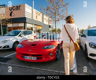 Straßburg, Frankreich - Oktober 15, 2017: Ansicht der Rückseite des Jungen Französischen Frau wandern in der Nähe von roten Cabriolet convertible Dodge Viper Auto vor og der Schauraum Autohaus geparkt Stockfoto