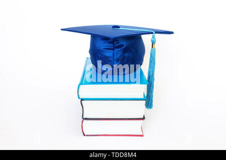 Blaue Graduierung Deckel auf Bücher auf weißem Hintergrund. Bildung Konzept. Stockfoto