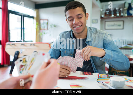Junger Mann Karten in Youth Club Stockfoto