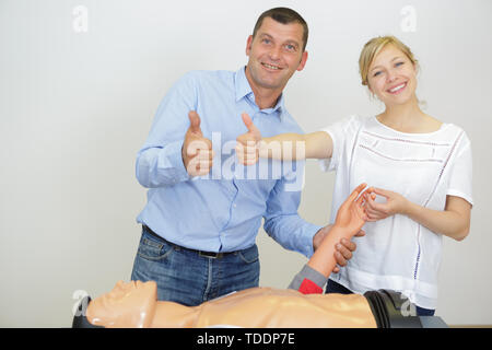 Gerne Studenten nach dem Üben HLW-Brust Kompression auf Dummy Stockfoto