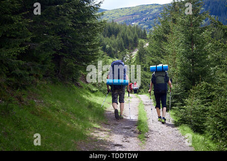 Abenteuer, Reisen, Tourismus, Wandern und Menschen Konzept - Gruppe von Freunden zu Fuß mit Rucksack von hinten. Stockfoto