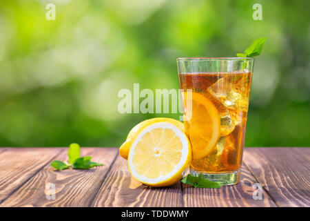 Glas aus Eis Tee mit Minze und Zitrone auf hölzernen Tisch im Freien Stockfoto