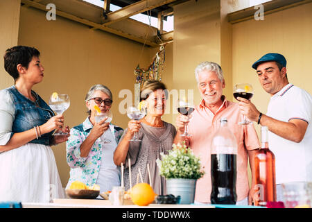 Fröhliche Gruppe von gemischten Alters ältere Erwachsene Freunde genießen und Feiern mit einem großen Glas und Cocktails oder Wein zu Hause - reife Freunde während der pa Stockfoto