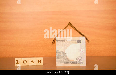 Haus aus der indischen Währung Notes und Darlehen in Holzblock Buchstaben auf Holz- Hintergrund. Stockfoto