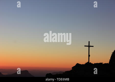 Sonnenuntergang in den Schweizer Bergen mit einer wundervollen rot gefärbte Himmel und ein gipfelkreuz Stockfoto