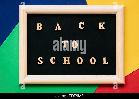 Zurück zu Schule Text geschrieben Holz Buchstaben auf schwarz Tafel in Rahmen. Konzept von Bildung, Einschulung, zurück in die Schule. Bunten Hintergrund Stockfoto