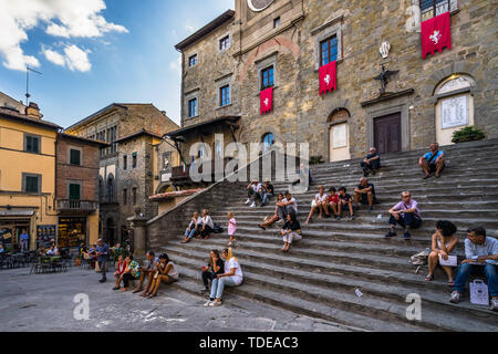 Die Menschen genießen Sie die lebendige Atmosphäre von Cortona sitzen auf der Treppe des Rathauses Gebäude (Palazzo Comunale). Cortona, Arezzo Provinz, Toskana Stockfoto