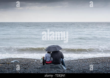 Aberystwyth Wales UK, Samstag, 15. Juni 2019 Deutschland Wetter: Ein paar haben den Strand für sich auf einem grauen und feuchten Nachmittag am Meer in Aberystwyth, West Wales, als die triste nass und sehr unsesonal Juni Sommer" Wetter seinen Einfluß auf das Land Foto Keith Morris/Alamy Live Nachrichten fort Stockfoto