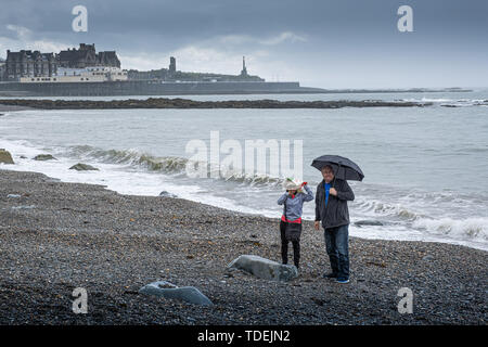 Aberystwyth Wales UK, Samstag, 15. Juni 2019 Deutschland Wetter: Ein paar haben den Strand für sich auf einem grauen und feuchten Nachmittag am Meer in Aberystwyth, West Wales, als die triste nass und sehr unsesonal Juni Sommer" Wetter seinen Einfluß auf das Land Foto Keith Morris/Alamy Live Nachrichten fort Stockfoto