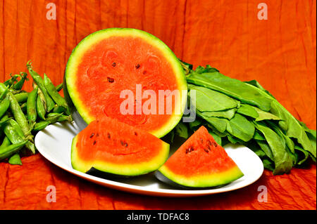 Eine gehackte Wassermelone in einem Teller mit Gemüse auf der Seite. Stockfoto