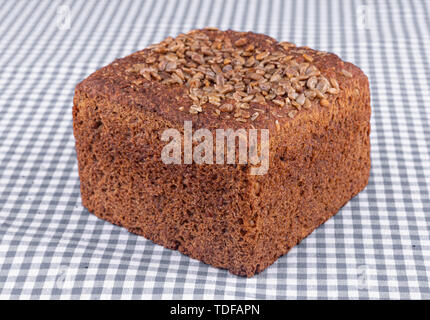 Stück Mehrkornbrot mit Sonnenblumenkernen oben, auf einer blauen Tabelle - Close-up Stockfoto